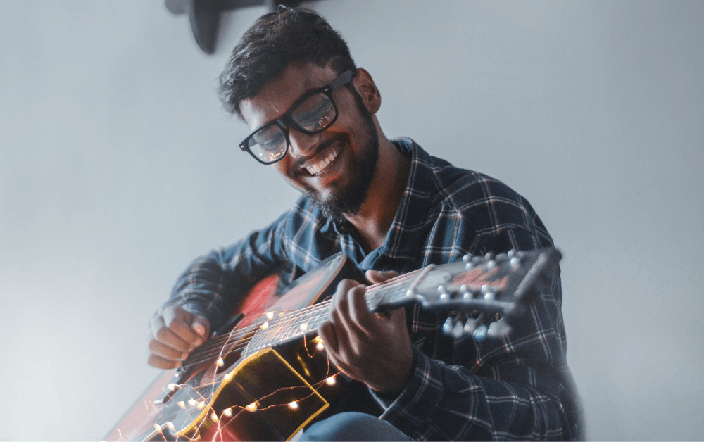 Man strumming guitar with lights around it